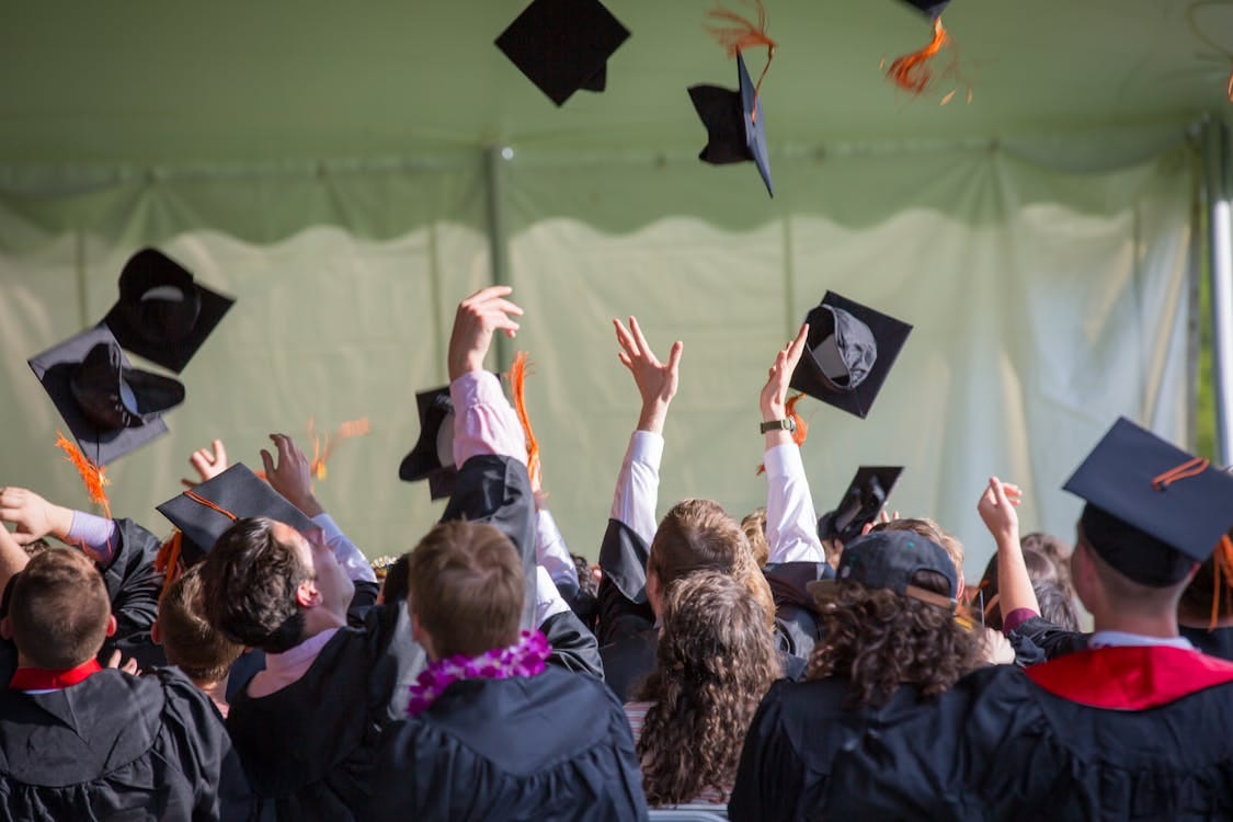 Free Group of graduates celebrating by tossing caps into the air during a graduation ceremony. Stock Photo