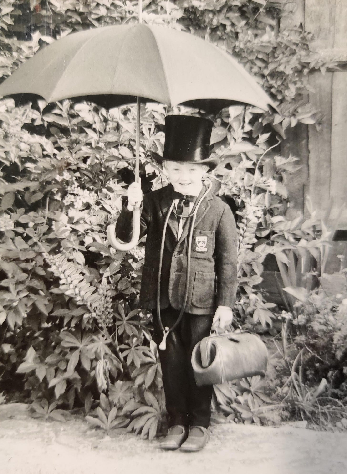 This is a black-and-white photo of the author, Gill McCulloch, taken by her father, Doctor Ken Warden, in 1969. Gill is dressed as Doctor Foster for a school play and is carrying her father's medical bag and a black umbrella.