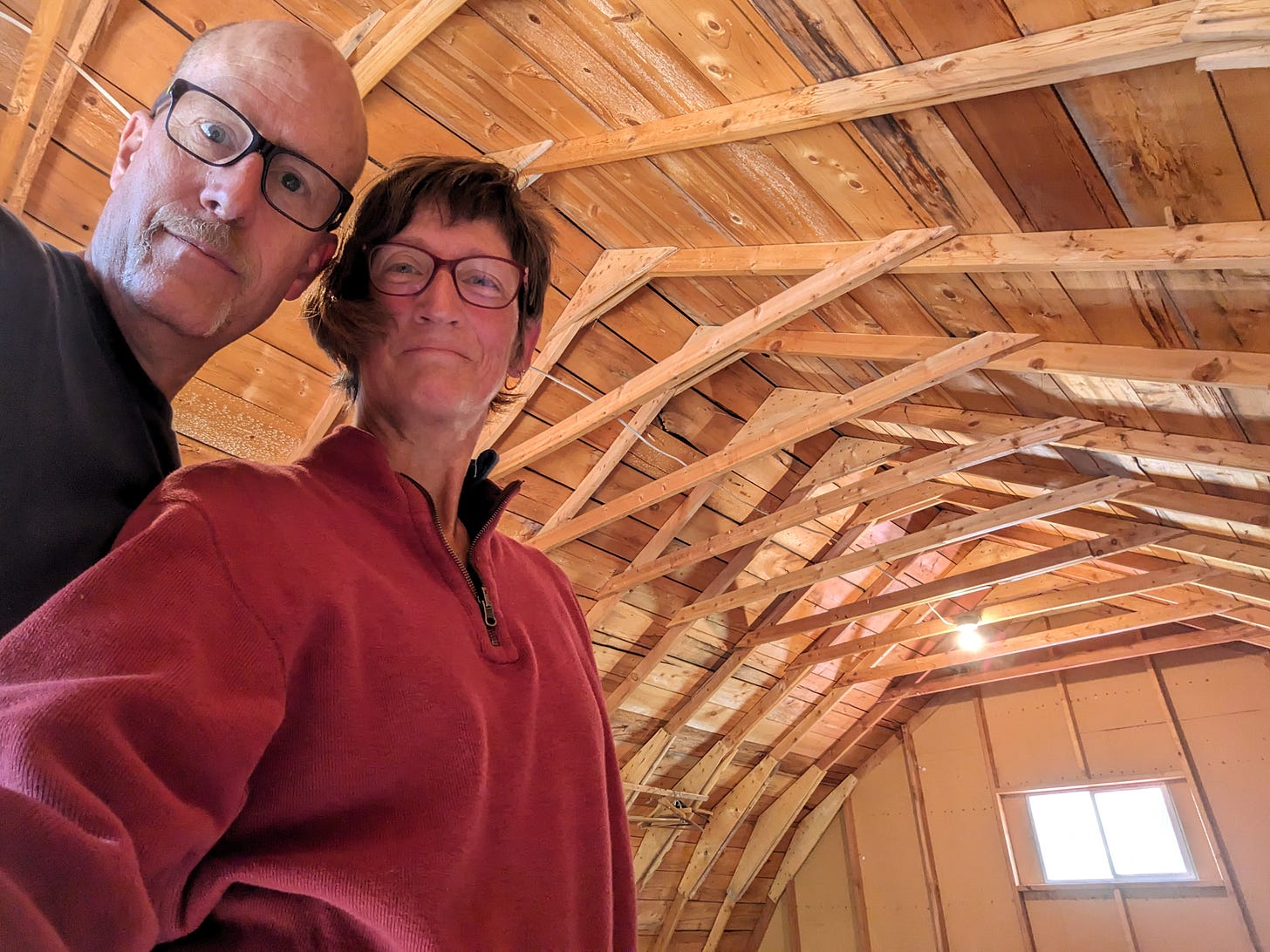 Andy and Sherry standing in the rough-hewn loft of a wooden barn.. The barn is empty