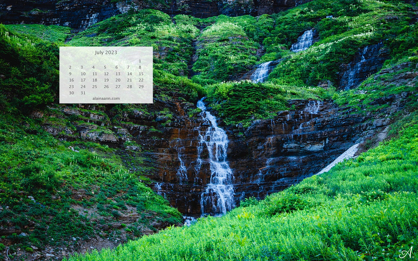 A tiny waterfall cascading over lush green vegetation and rocks. A July 2023 calendar is overlayed in the top left corner.