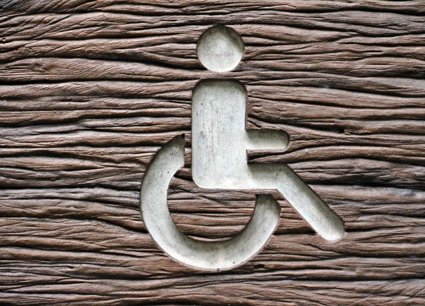 Wheelchair symbol carved into textured wood