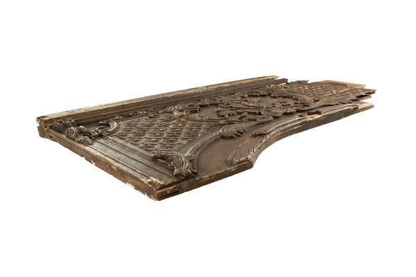 A movie prop made to look like an ornately decorated fragment of a wooden door frame.
