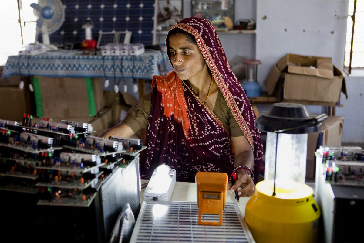 Indian woman works at a desk full of tech equipment inside a brightly lit building