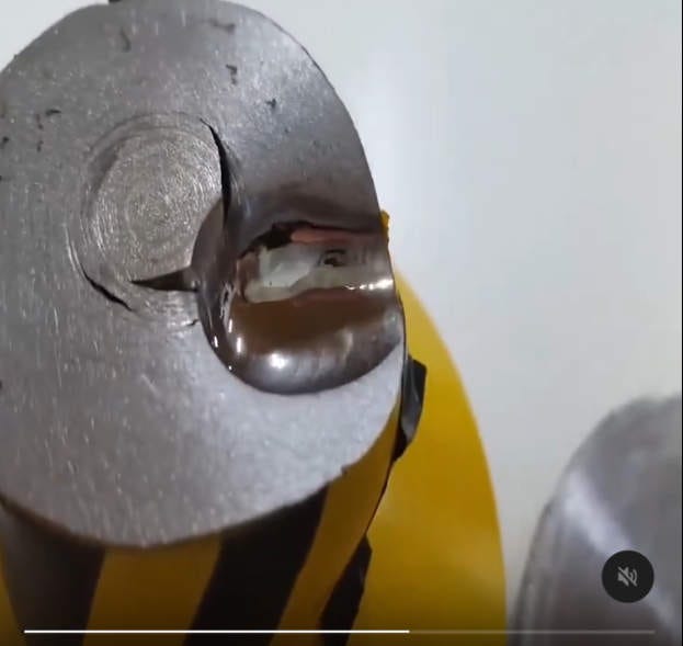 The deeply dented steel head of a hydraulic press.