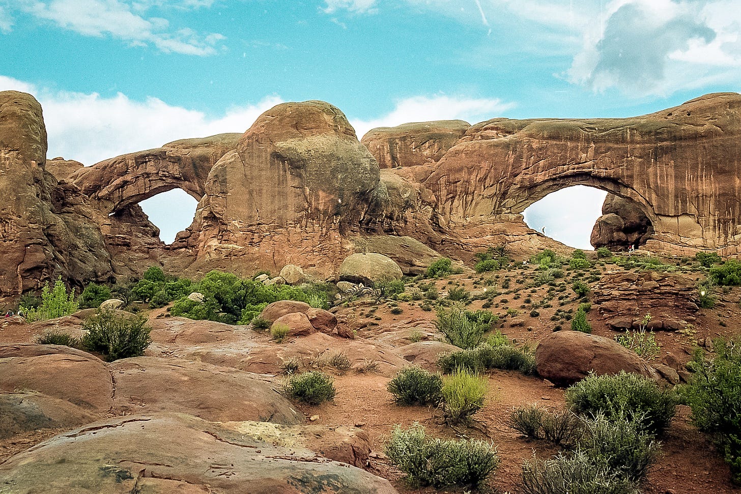 An analog photo of Natural Bridges Monument from 1997, featuring two large stone arches in a rugged, desert landscape. The image reflects the concept of pausing and reflecting, like natural formations shaped over time, now digitized by Jay Siegmann. An analog photo of Natural Bridges Monument from 1997, featuring two large stone arches in a rugged, desert landscape. The image reflects the concept of pausing and reflecting, like natural formations shaped over time, now digitized by Jay Siegmann.