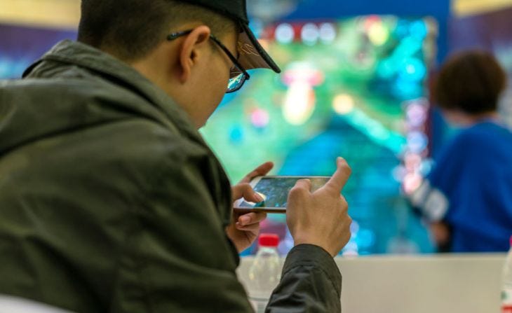 Young players compete in a battle match of the mobile game Arena of Valor, held in a shopping mall.