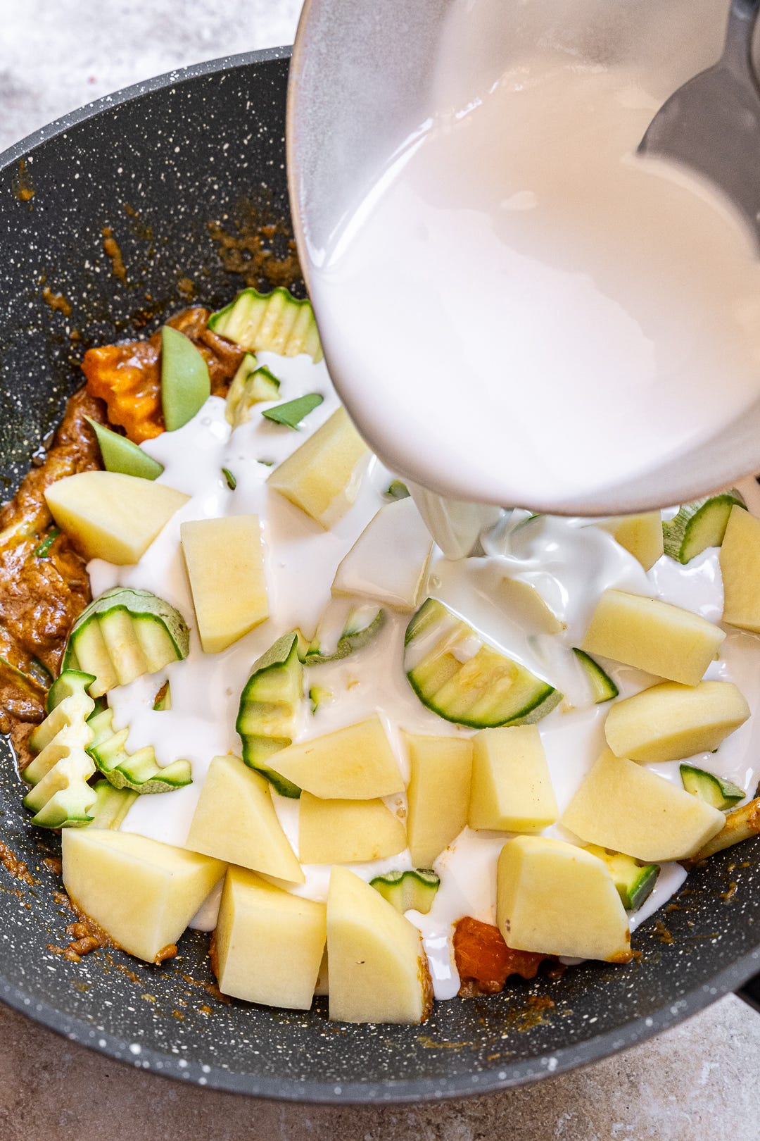 Pouring coconut milk in wok