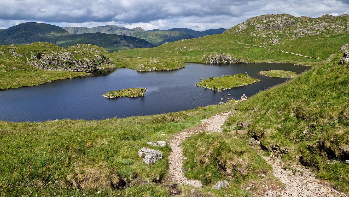 Tarn with small islands surrounded by green hills