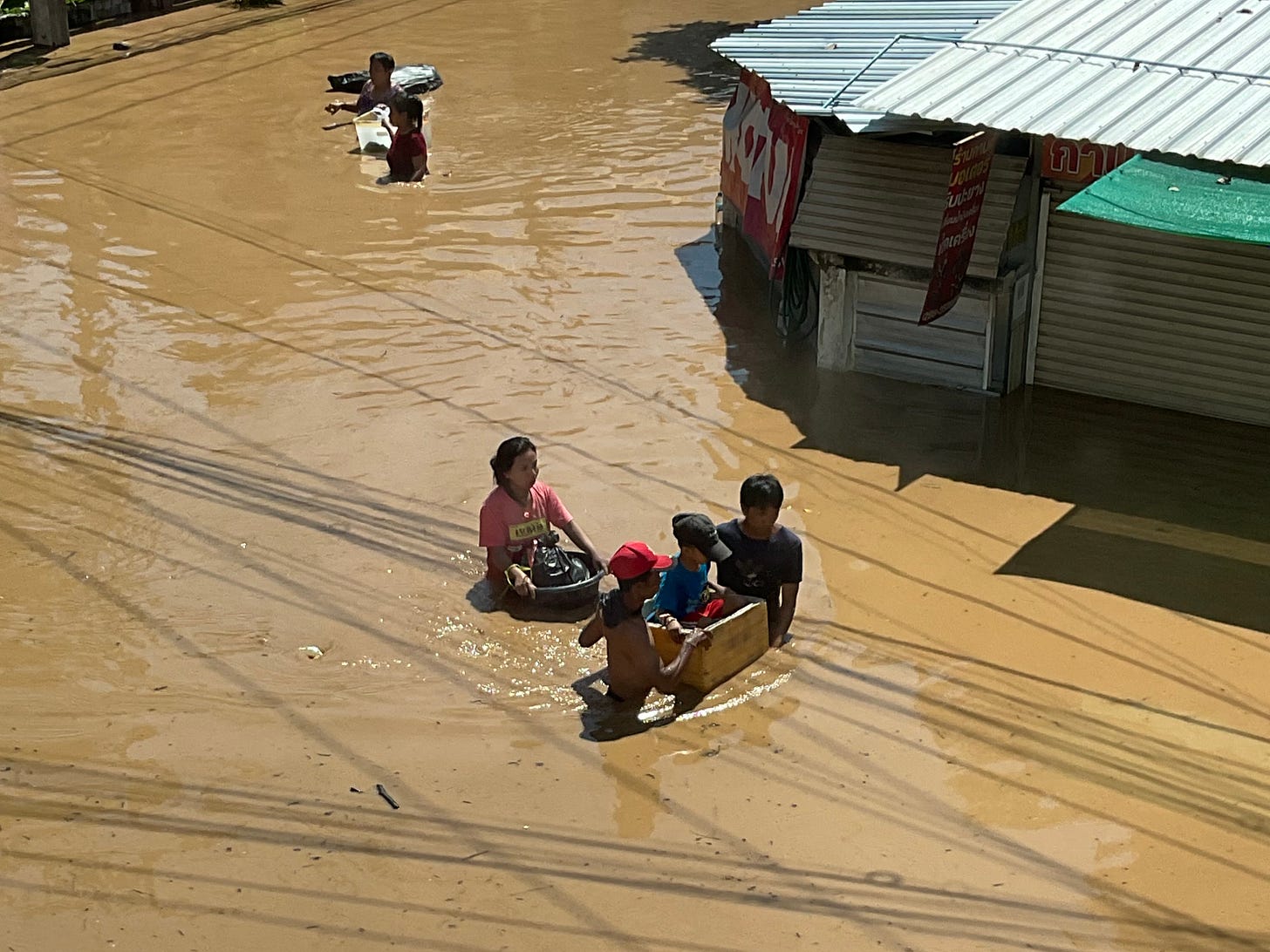 Flooded streets, with a young child being transported in a wooden box, Chiang Mai, Thailand