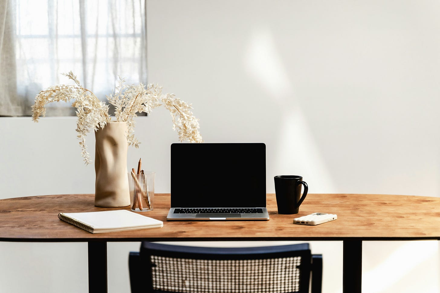 desk with laptop and vase and writing implements