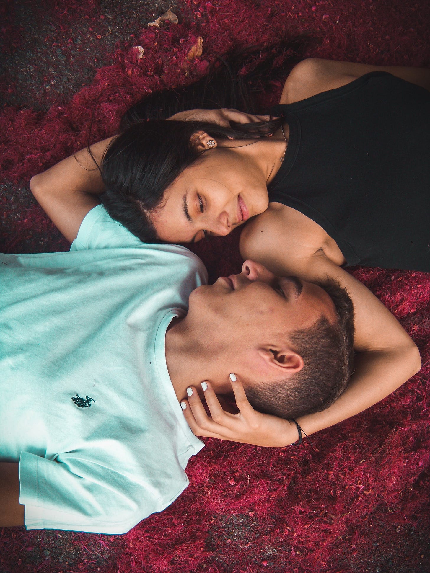 Man and woman lying on red carpet of flowers