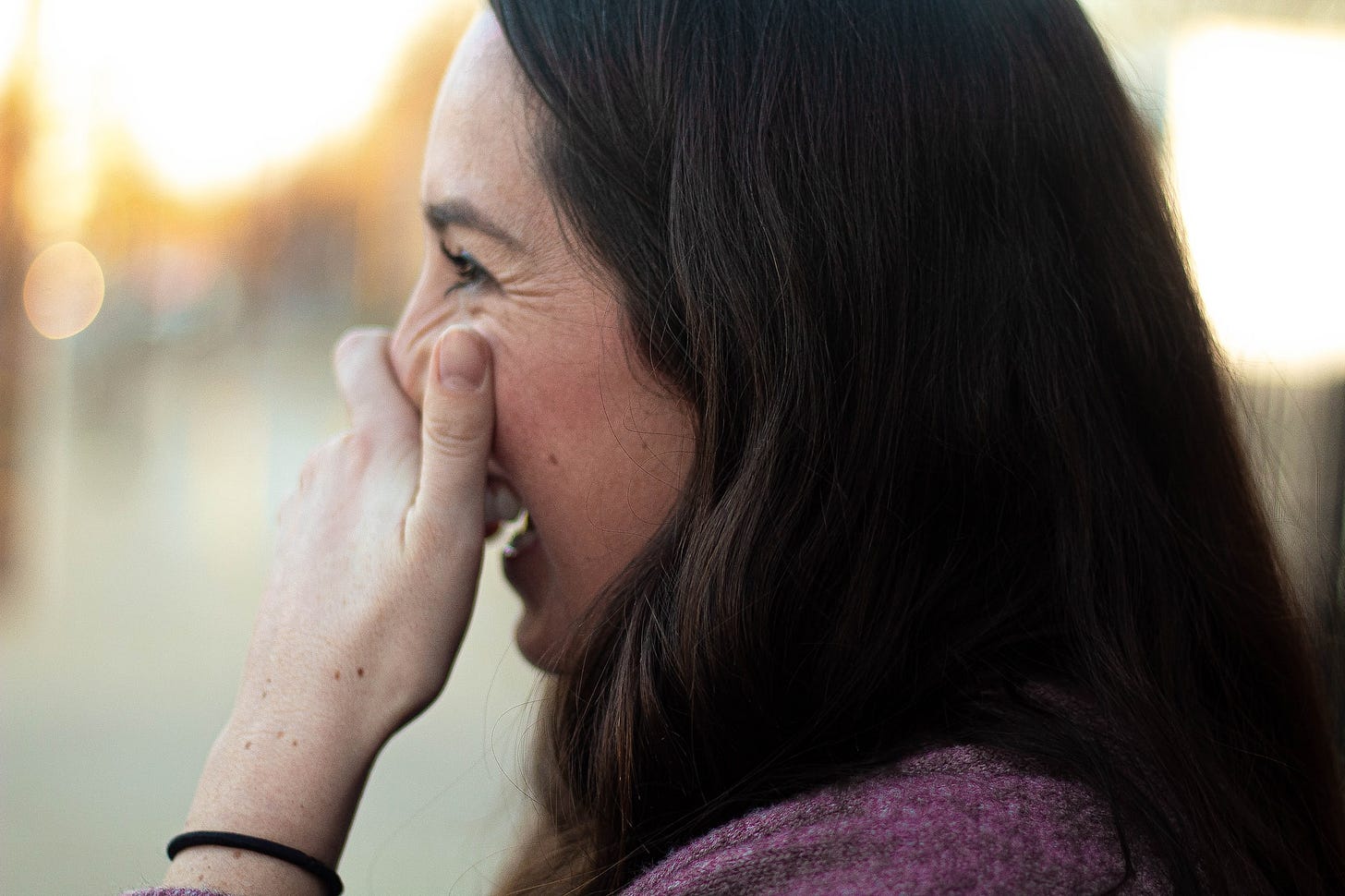 brown haired girl covering her mouth laughing