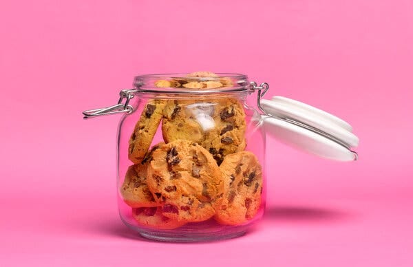 A picture of a glass jar holding chocolate chip cookies. 