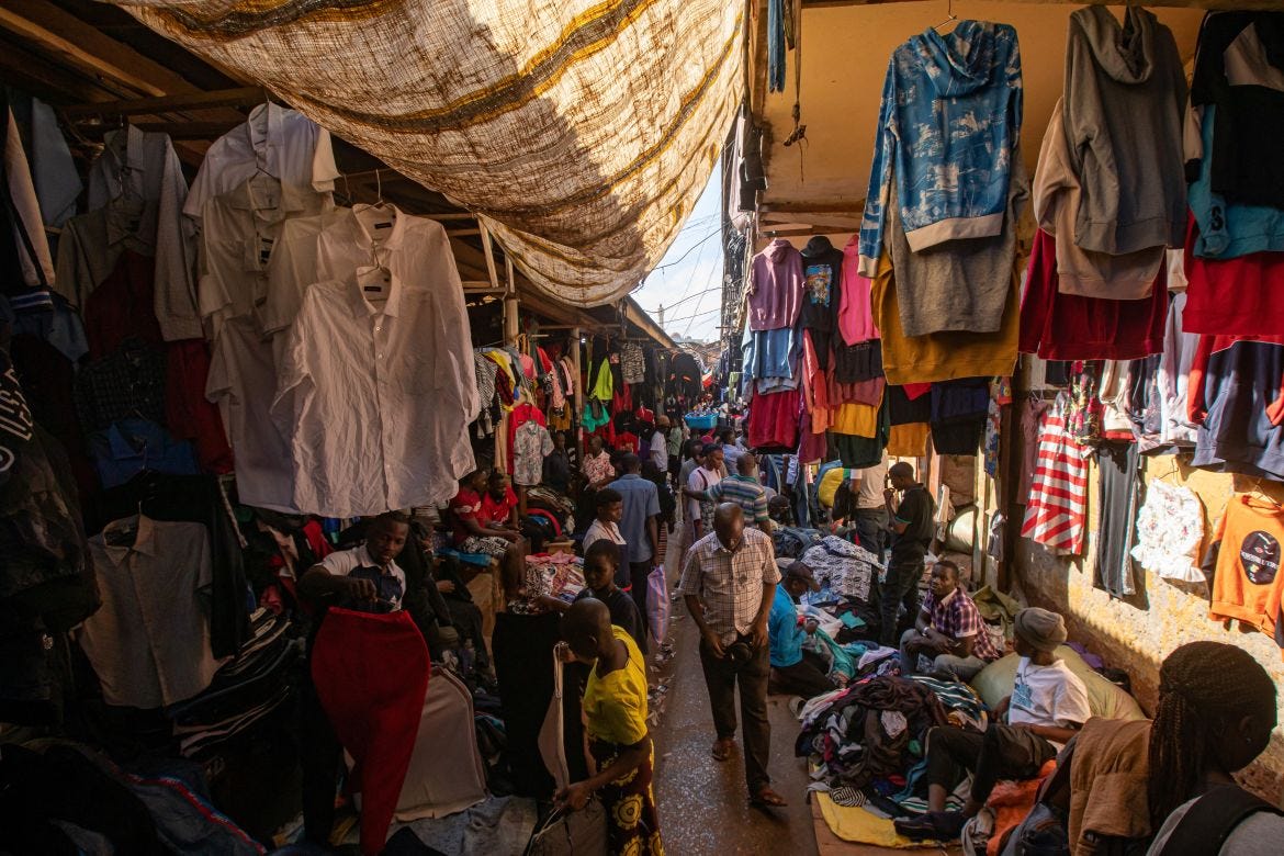 Sellers offering second-hand clothes wait for costumers at a market in Kampala.