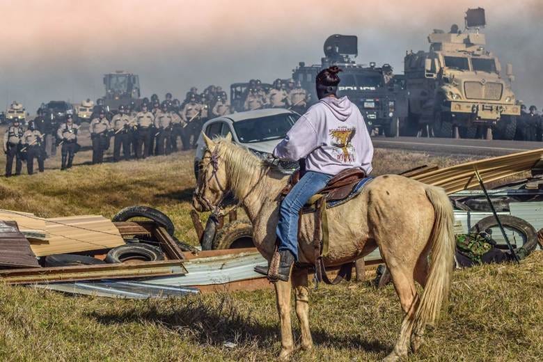 Lakota horseman faced line of law enforcement. Photo by Ryan Vizzions. Lakota horseman faced line of law enforcement. Photo by Ryan Vizzions.