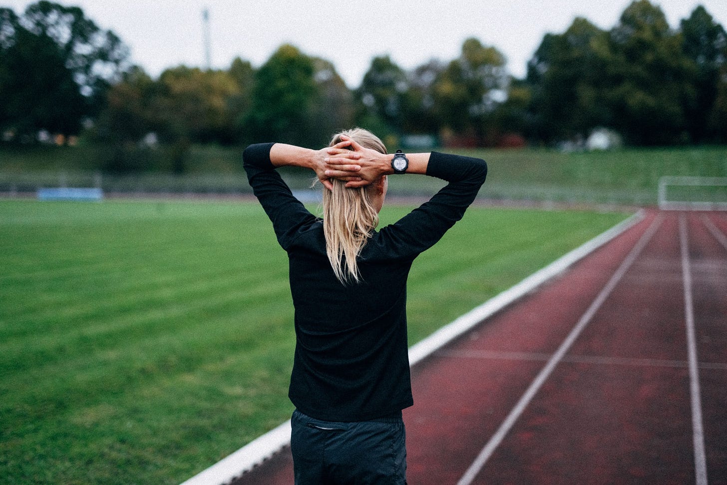 female runner on a track holding her hands over her head