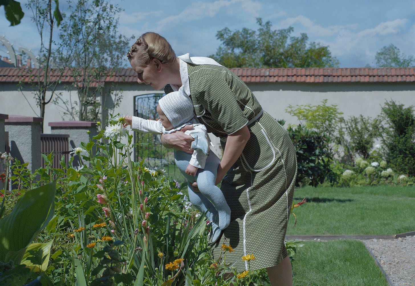 Hedwig Hoss (Sandra Huller), holding her baby and tending to the garden