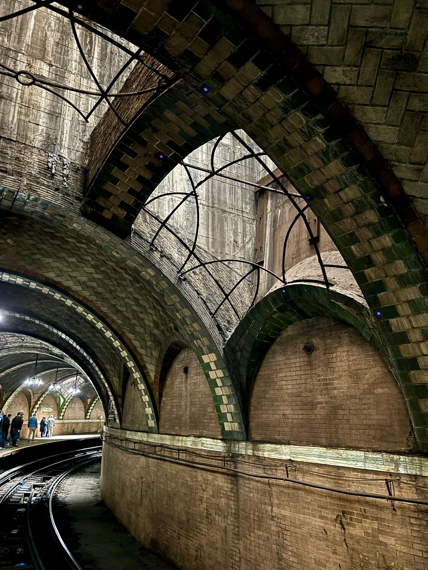 Sunlight coming in through windows in the vaulted ceiling over the subway tracks.