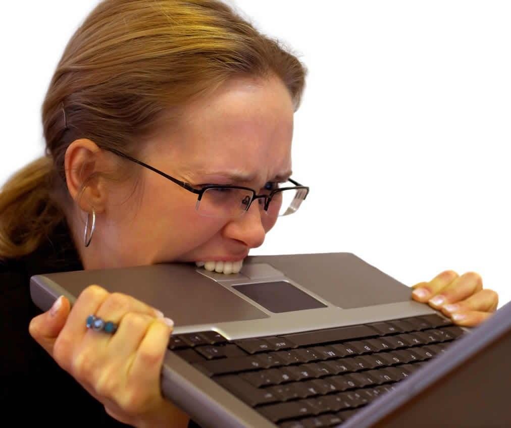 A stock photo of a woman biting a laptop computer.