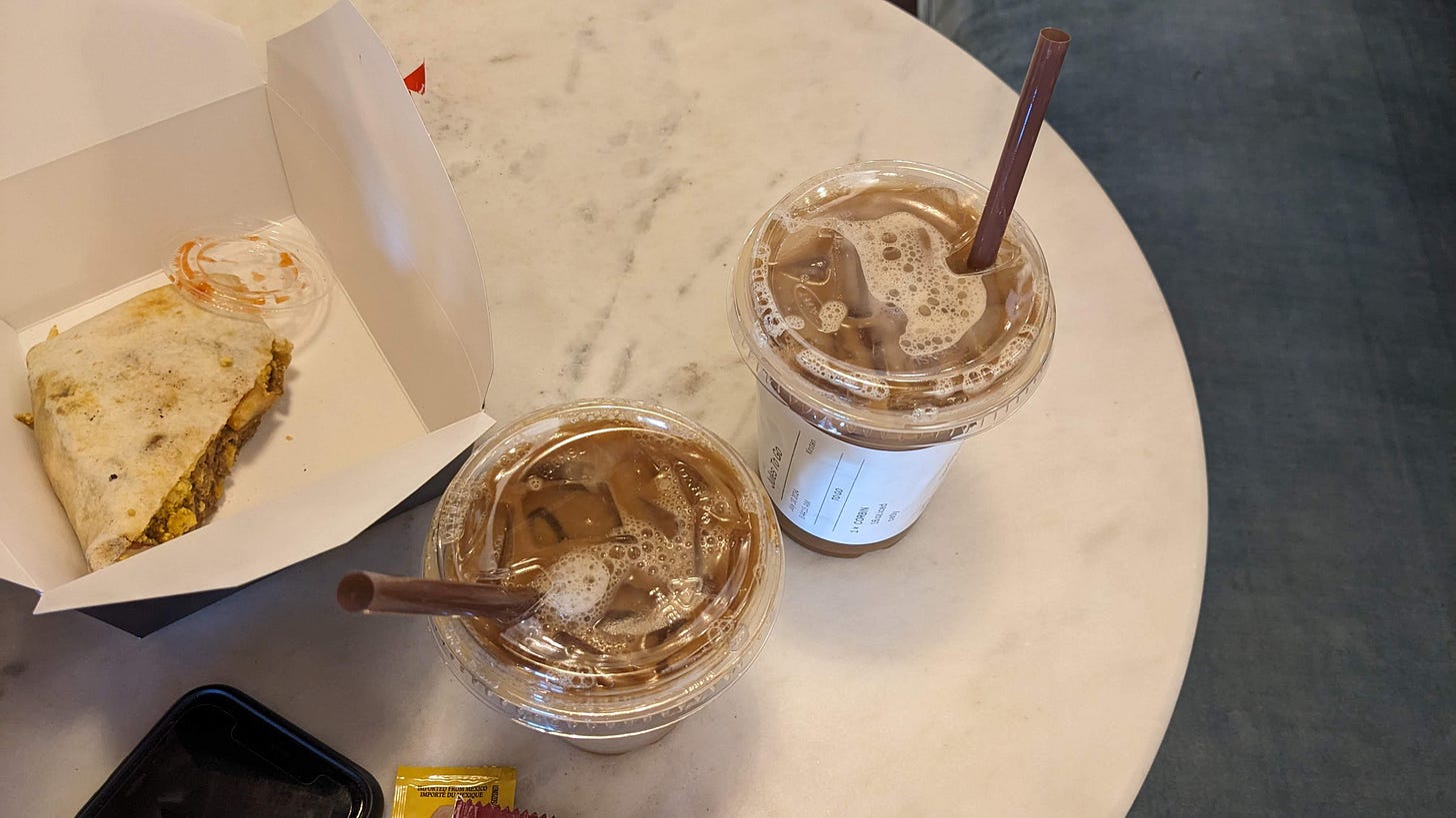 2 cold brew coffees and a vegan breakfast burrito being eaten