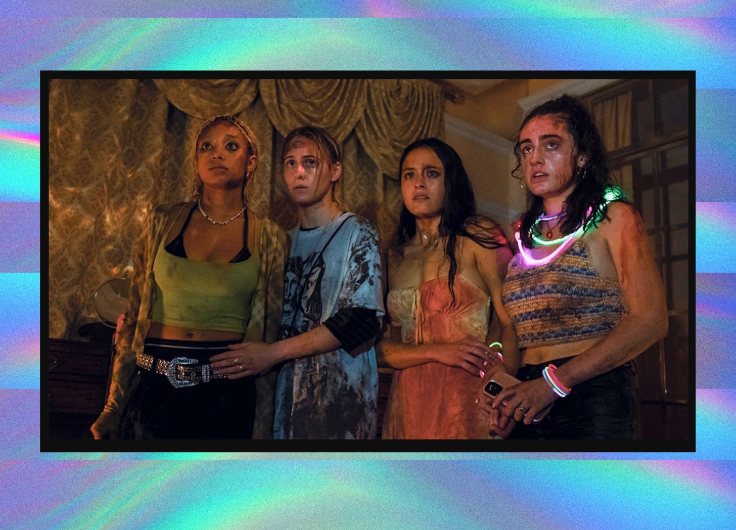 A screenshot from Bodies Bodies Bodies overlaid on a groovy purple and blue background. The screenshot shows four of the main characters standing shoulder to shoulder, in various states of dishevelment. The women - wearing colorful, modern clothing, one with an array of glow stick necklaces - are looking in terror at something just off-screen.