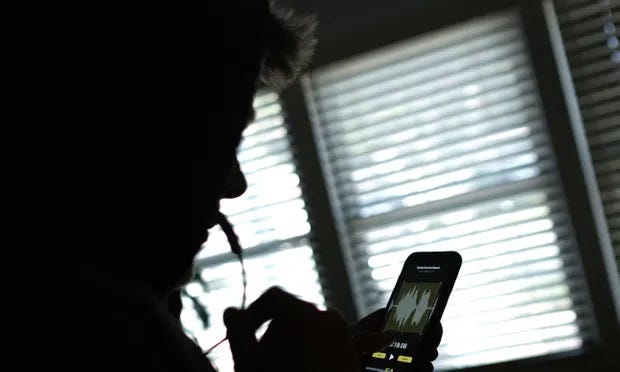 Silhueta de um homem segurando o celular e o microfone com um aplicativo para mudança de voz