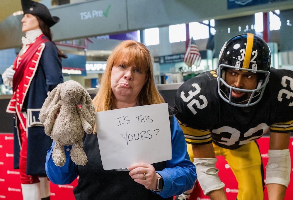 Pittsburgh International Airport staffer holds up a lost bunny with a sign that reads Is This Yours?