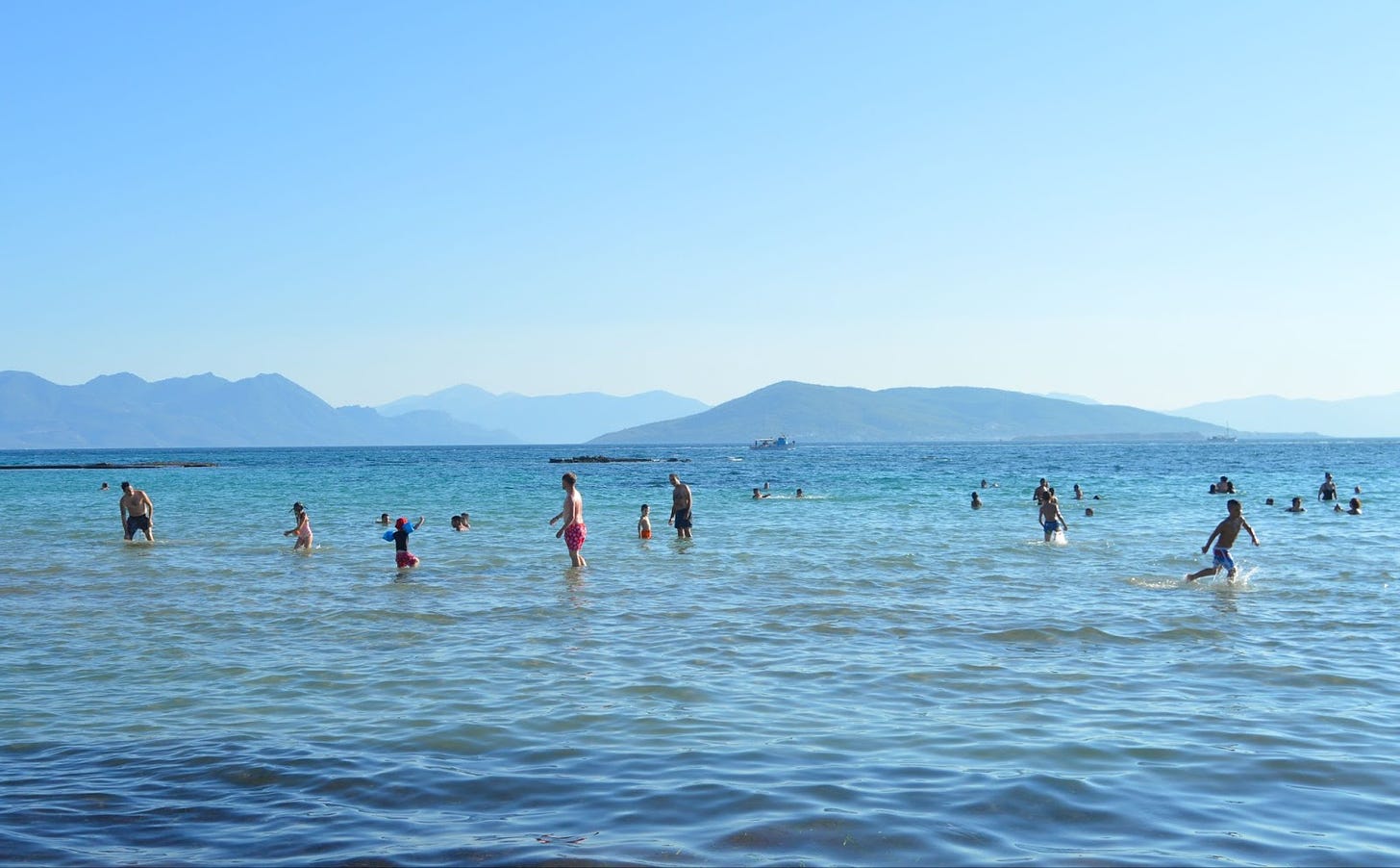 Greek Island, blue sky and blue water, people are swimming in the water