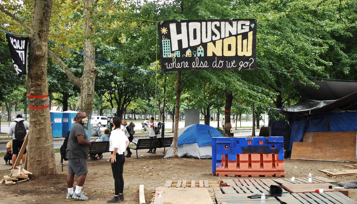 Housing Now banner at an encampment.