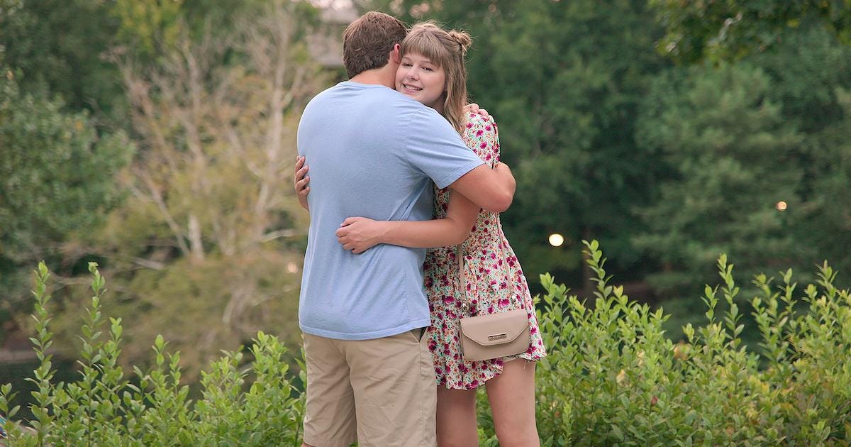 Still frame of Love On The Spectrum US Season 1, Kaelynn Partlow wearing a floral dress hugs a man in a blue t-shirt and tan pants in a field