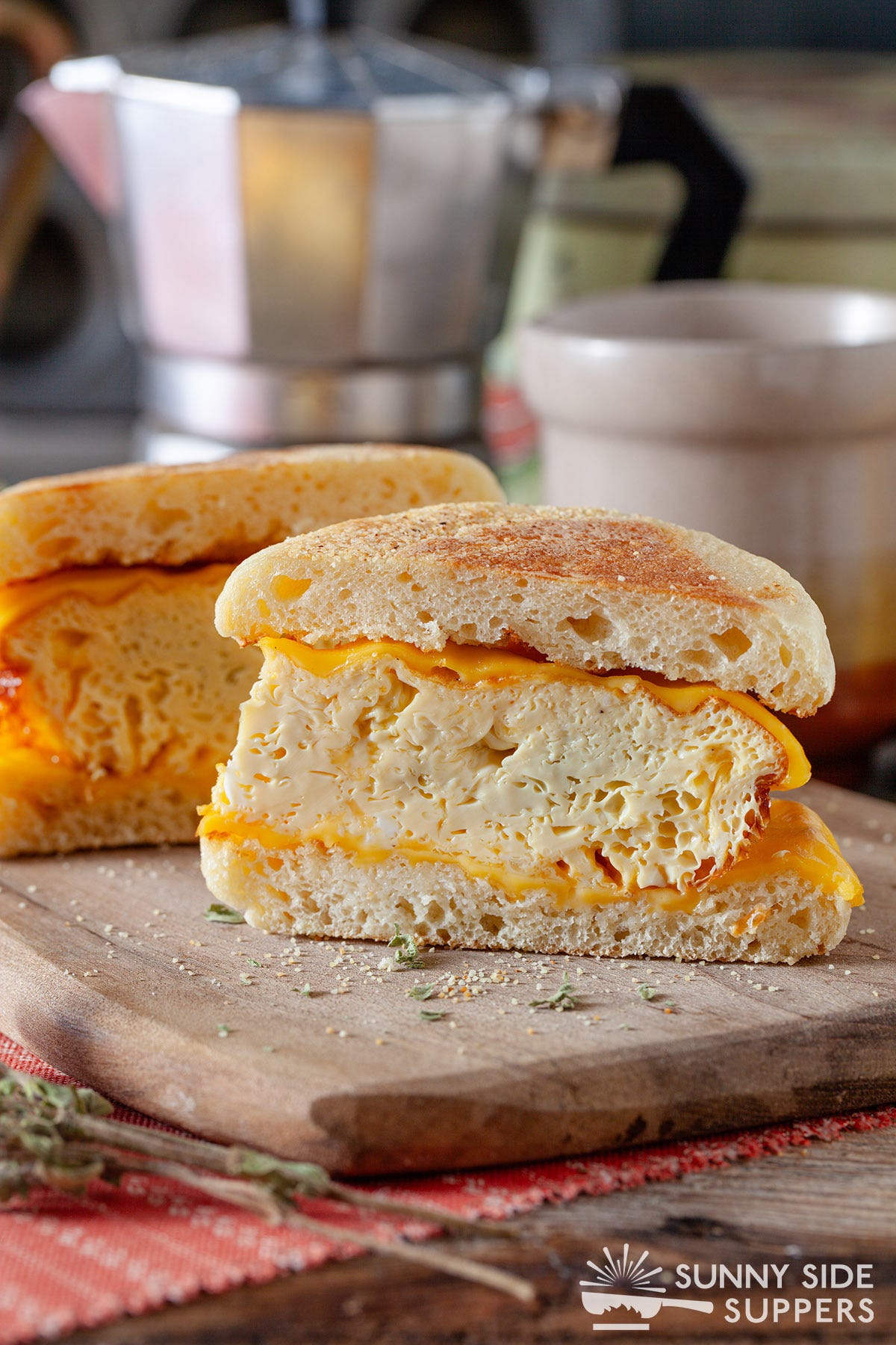 A breakfast sandwich sliced in half on a plate.