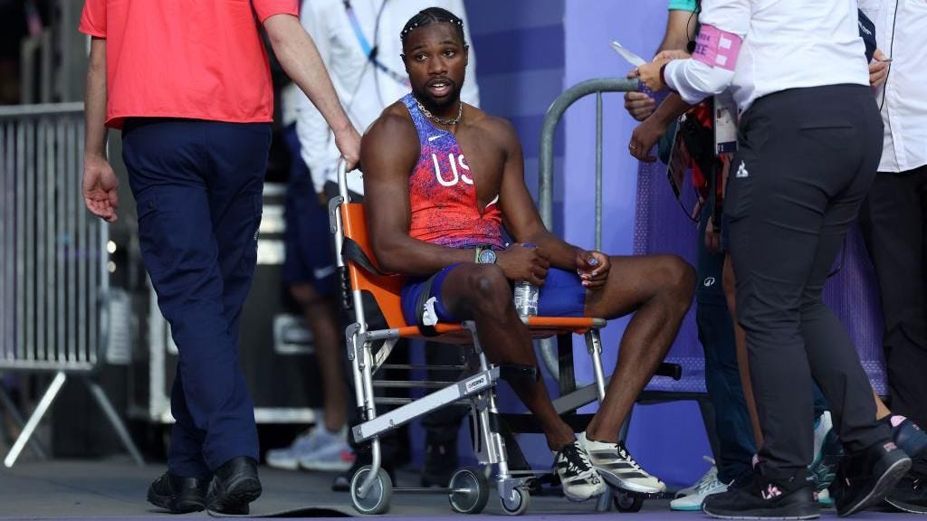 Noah Lyles is helped off the track in a wheelchair