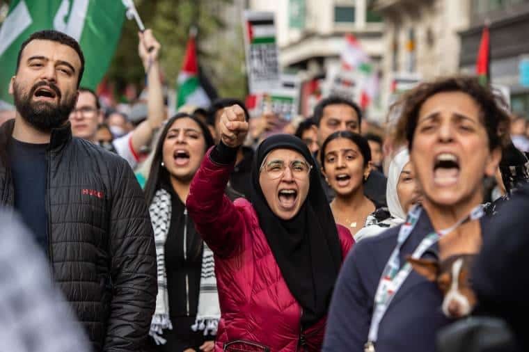 A crowd shot with a Muslim woman with a fist on the London Palestine march 