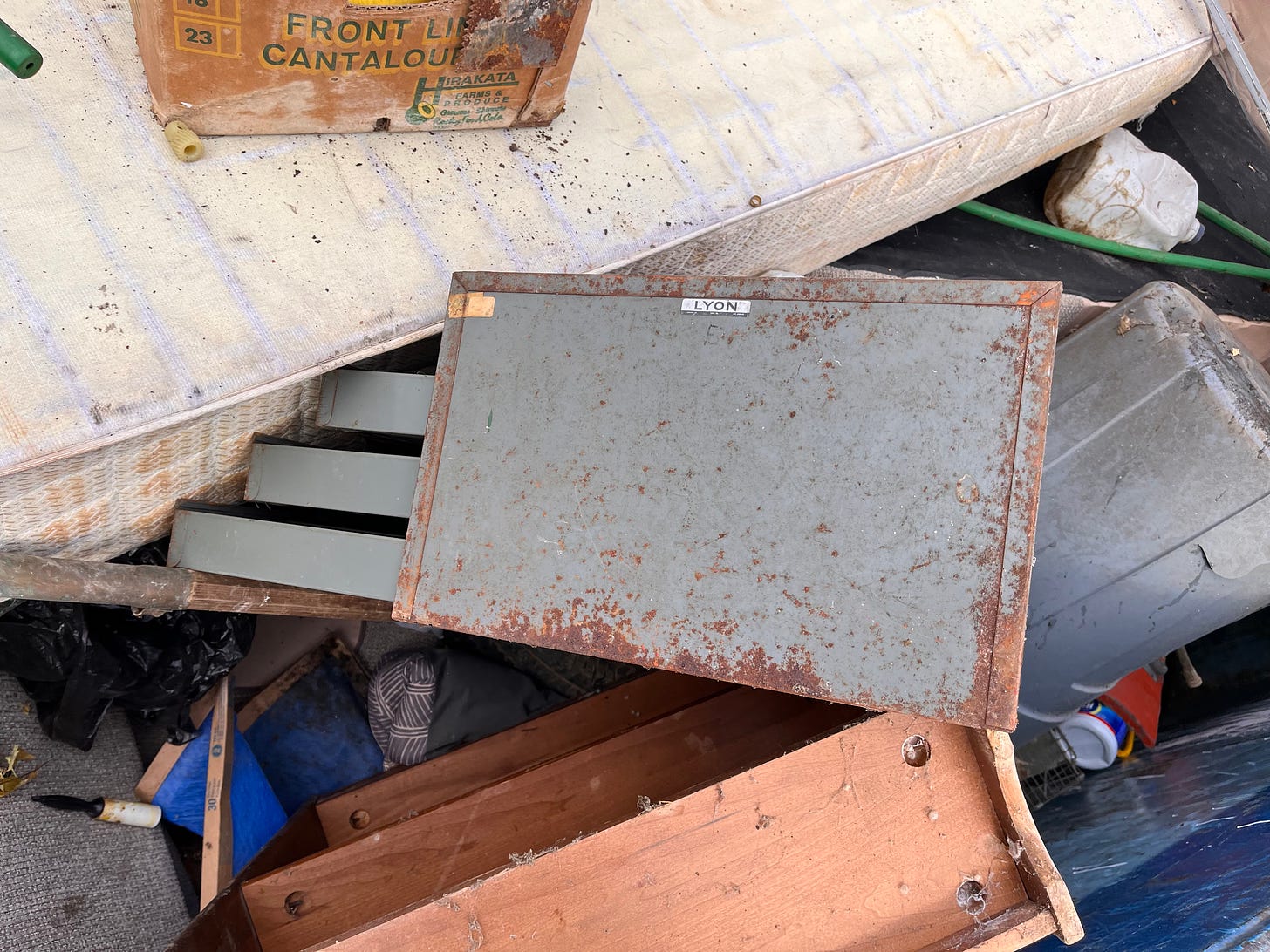 old metal parts cabinet sitting in a trash dumpster
