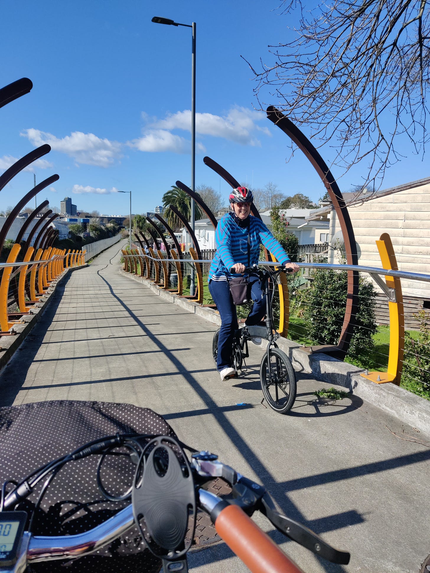 A photograph taken by someone on a bike, on the Western Rail Trail, with Rebekah on her biking coming the other way, going up-hill and smiling at the camera. 