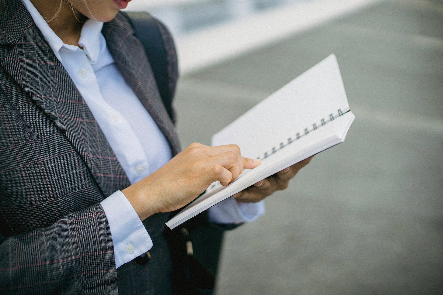 Woman in a blazer reading from a notebook