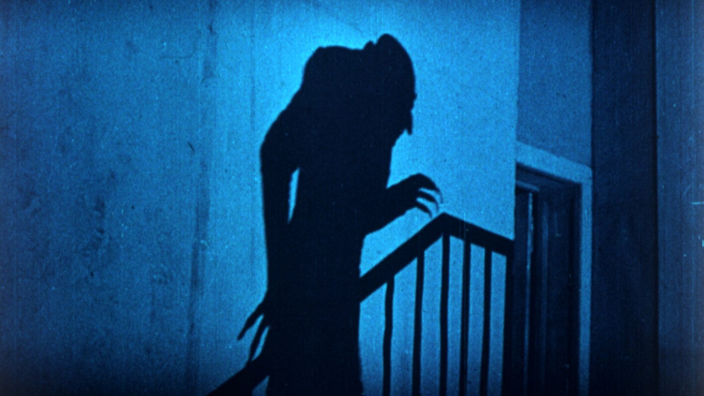a blue-lit stairway. the shadow of Count Olaf, bald with clawed fingers and a long, thin sillouette is cast against the empty wall.