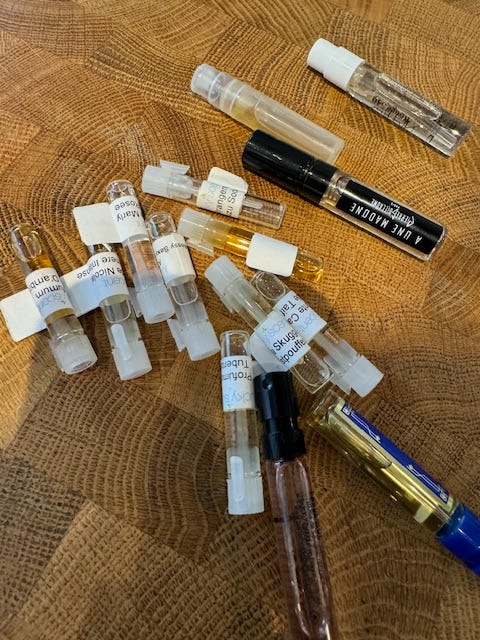 About ten tiny vials of perfume scattered on a wooden table