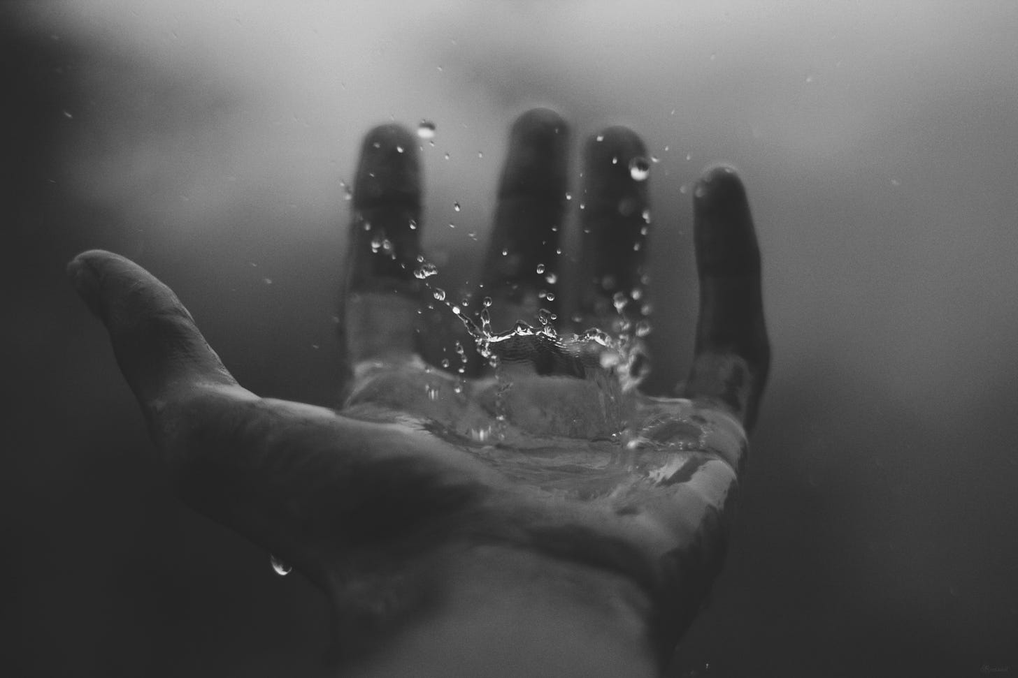 An outstretched hand with waterdrops falling into the palm