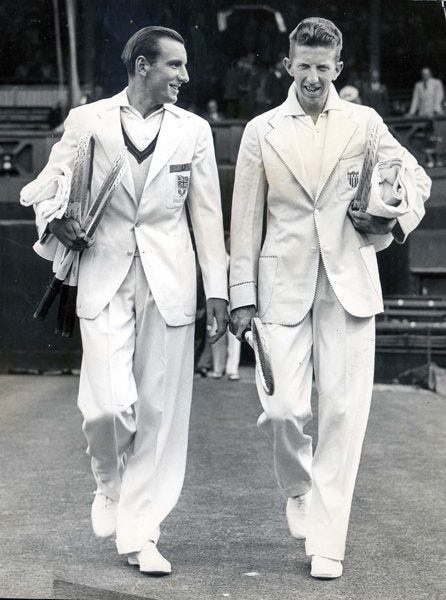 This may contain: two men in white suits walking on a tennis court