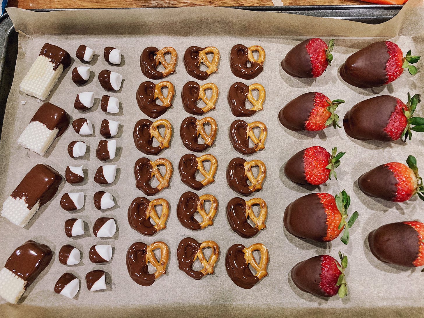 Tray with chocolate covered wafer cookies, marshmallows, pretzels, and strawberries.