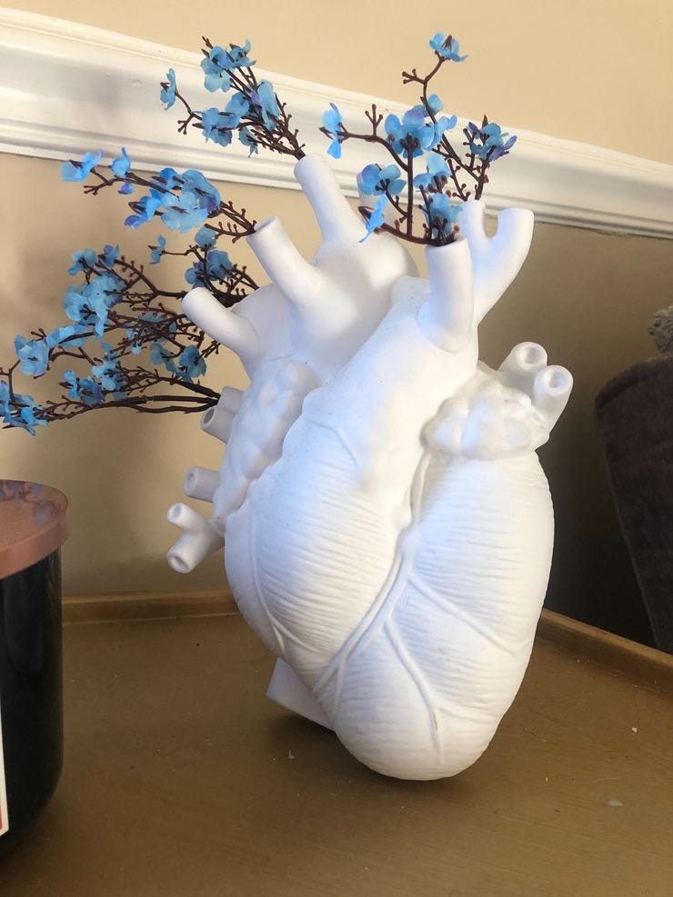 Realistic white ceramic human heart vase with flowers poking out 
