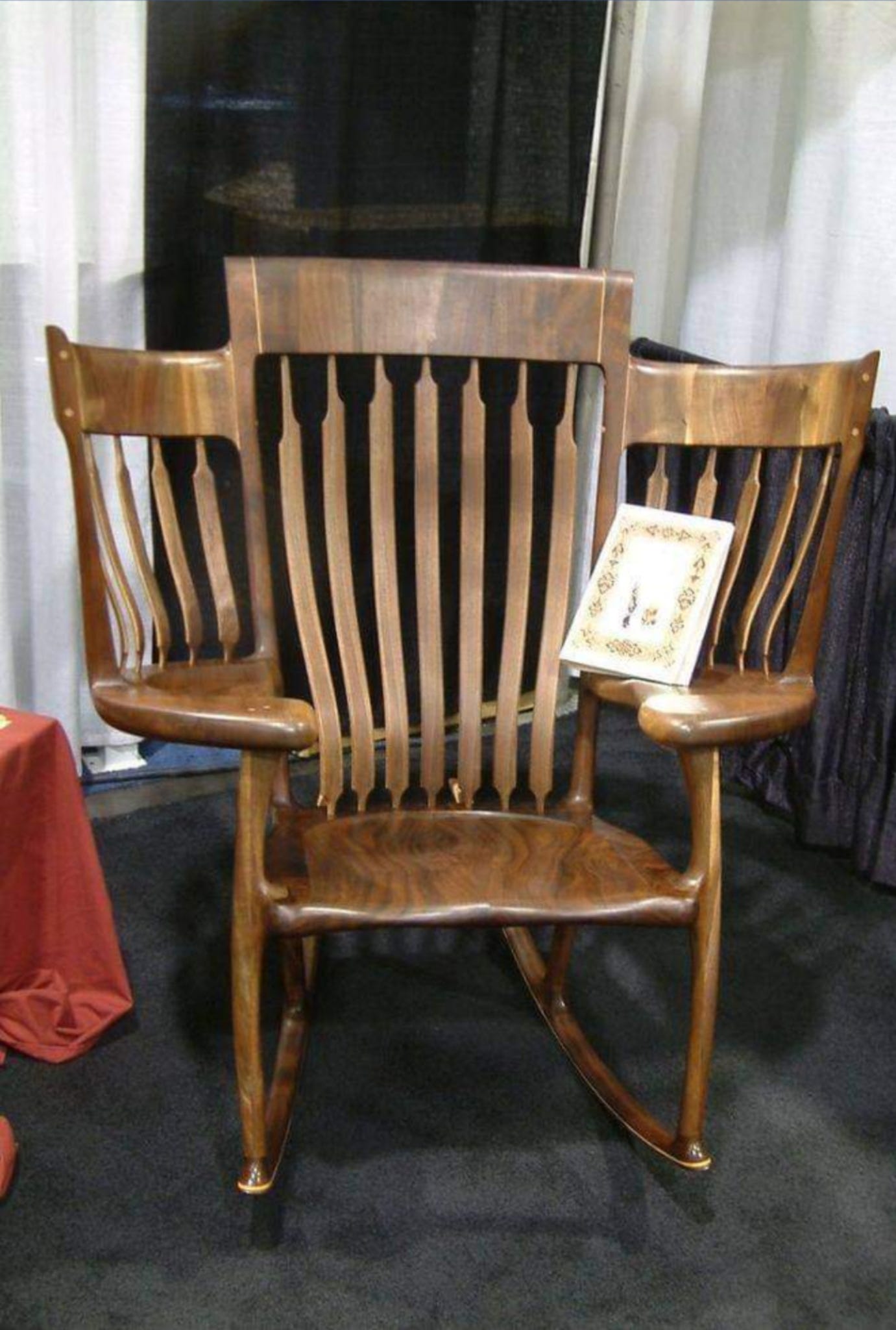 a rocking chair with two extra seats with their own backrests where arm rests usually are