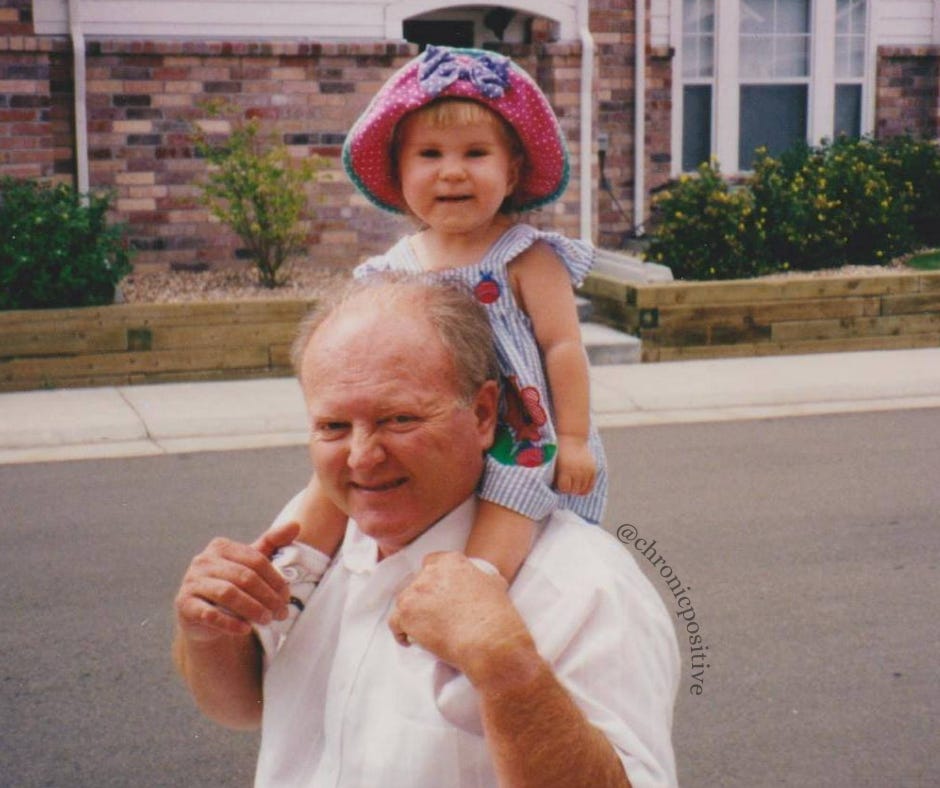 A picture of Sky and her grandpa when she was a toddler. She is sitting on his shoulders, wearing a pink hat and a cute 90s jumper. Her grandpa is holding onto her legs, and they are both smiling.