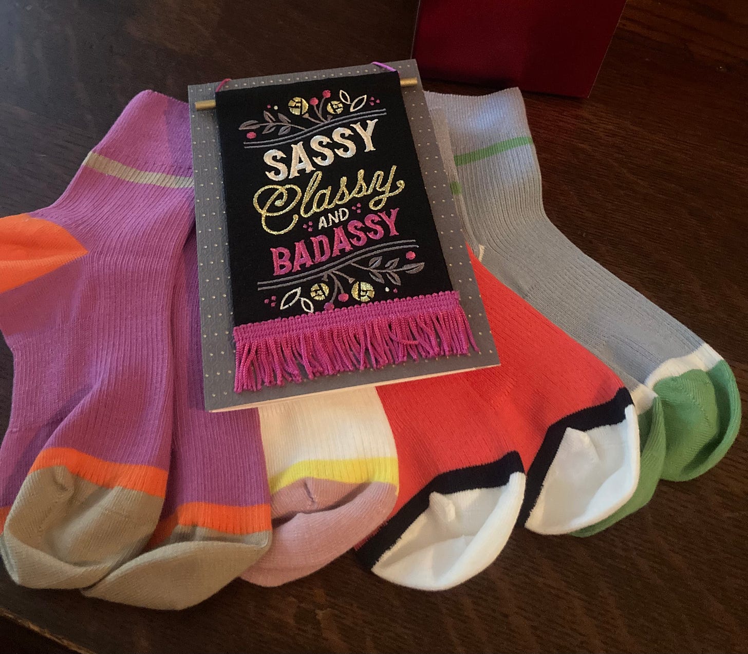 Four pair of colorful ankle socks fanned out with a card on top of them that says "Sassy, Classy, and Badassy." 