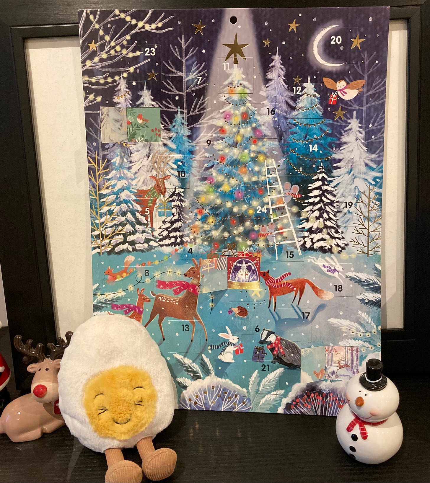 Photo of a beautiful paper advent calandar flanked by a ceramic rudolph, Dippy the soft toy egg, and a ceramic snowman