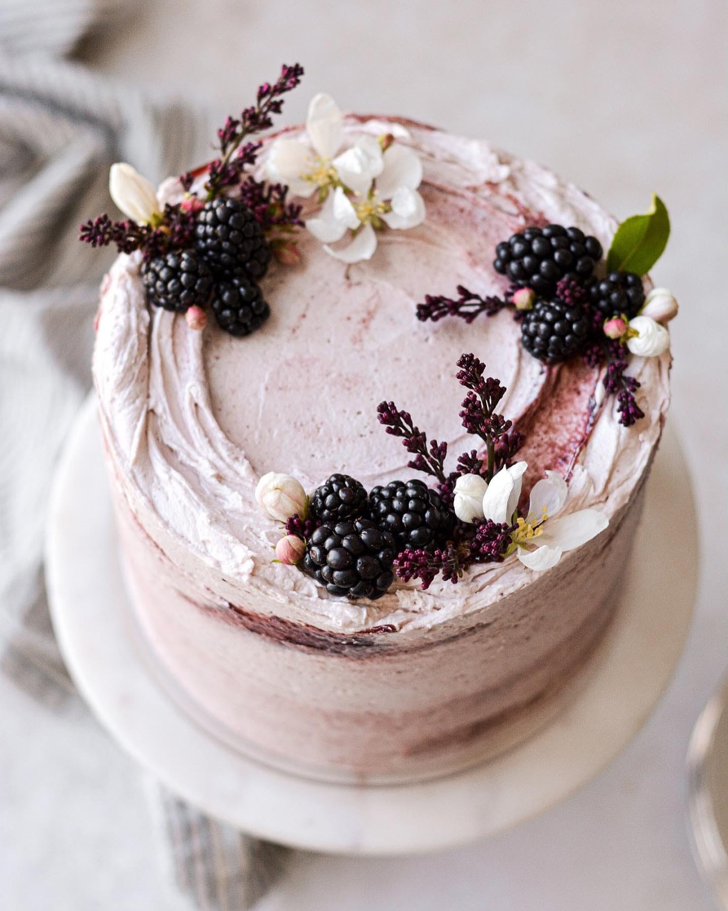 pink-swirled cake with blackberries and floral decorations
