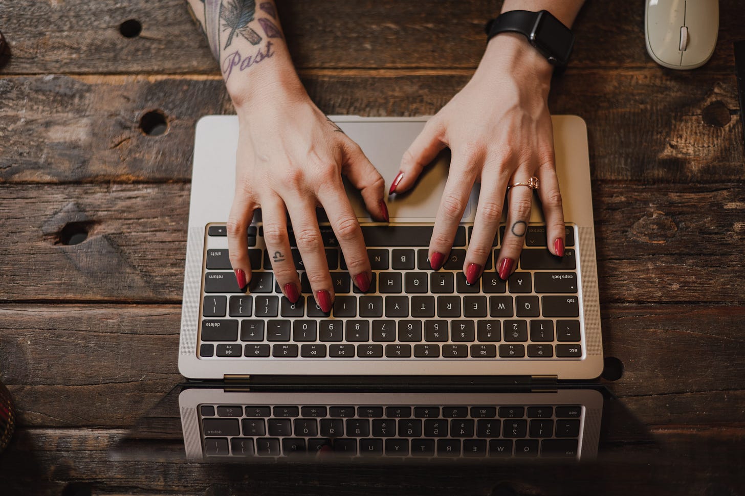 Kate’s tattooed hands typing on her laptop, by Amanda Macchia.