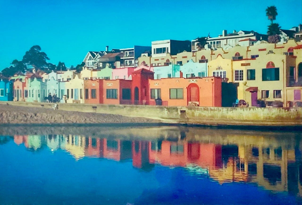 Vintage photo of Venitian Courts apartments at Capitola Beach with multicolored units reflected in the water.