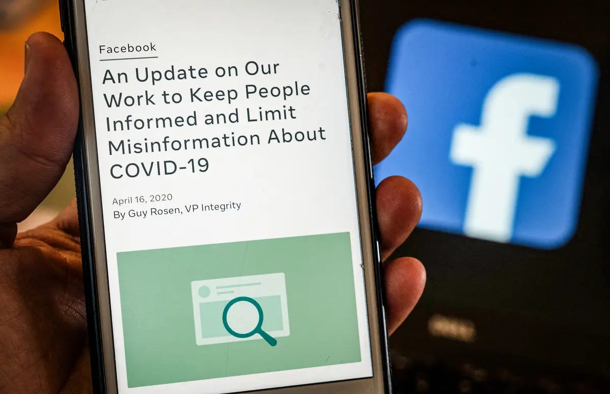 A smart phone screen displays a new policy on COVID-19 misinformation with a Facebook website in the background, in Arlington, Va., on May 27, 2021. (Andrew Caballero-Reynolds/AFP via Getty Images)